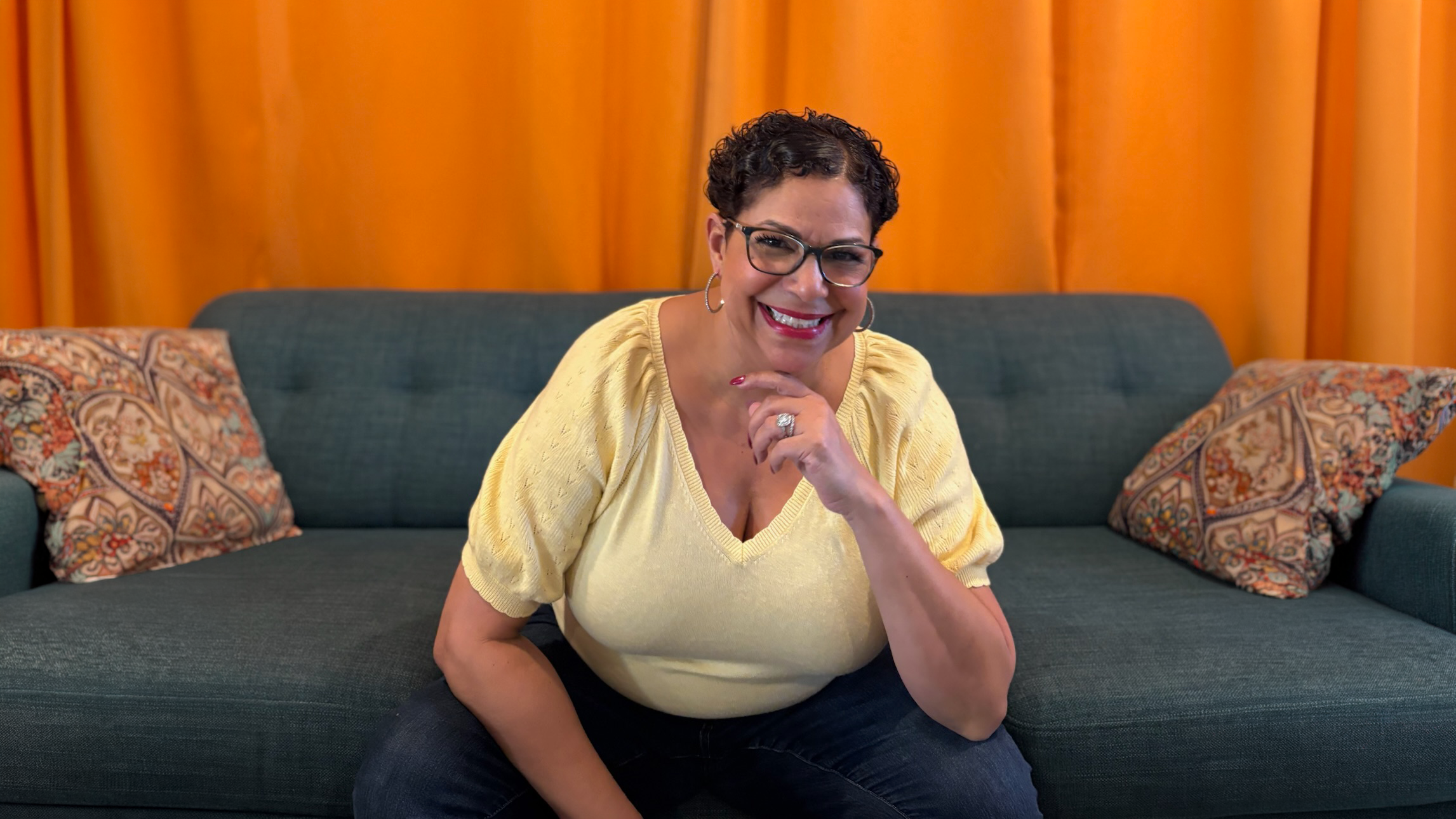 Lori Peacock on a couch in a yellow shirt